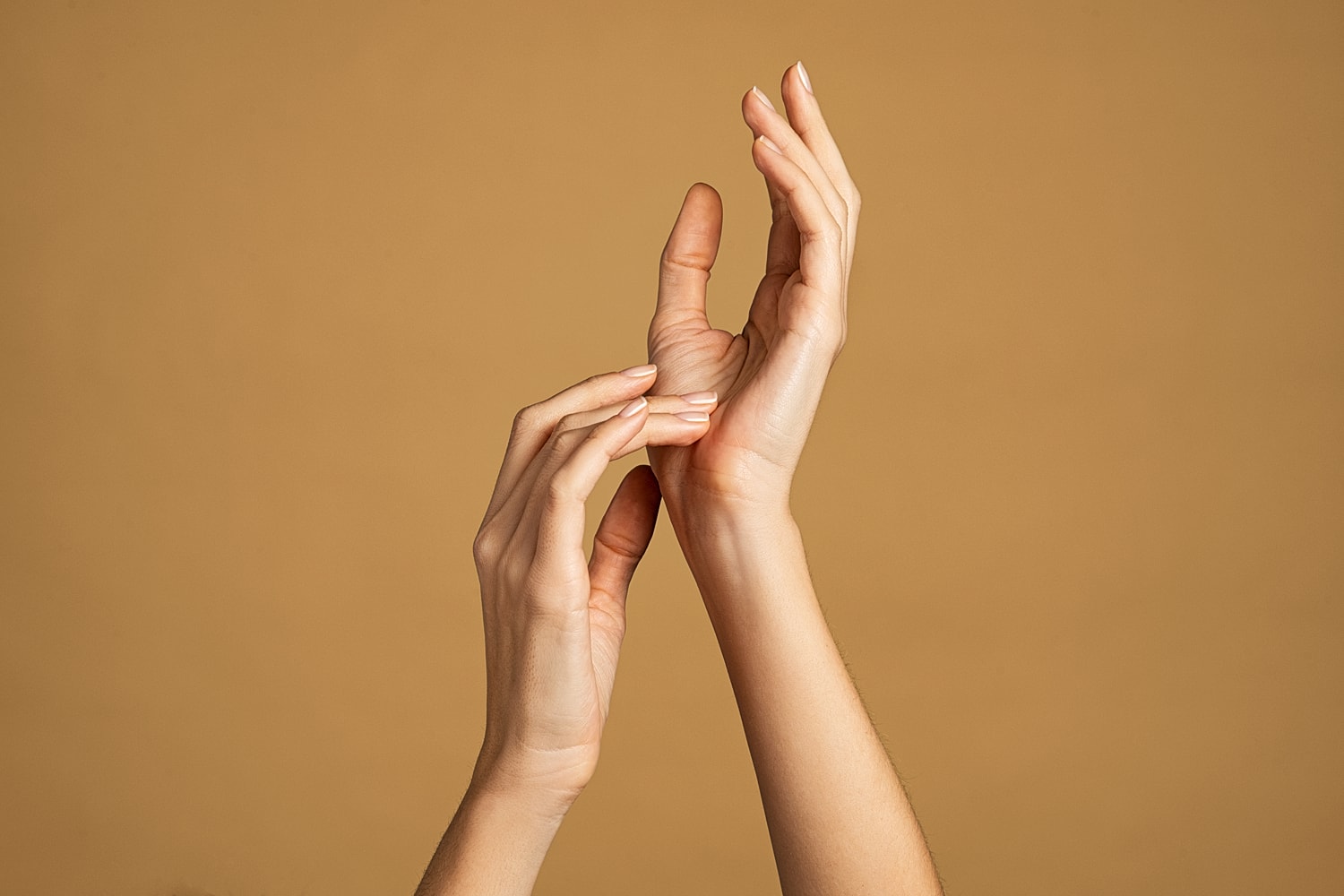 Hands interacting against a warm brown background.