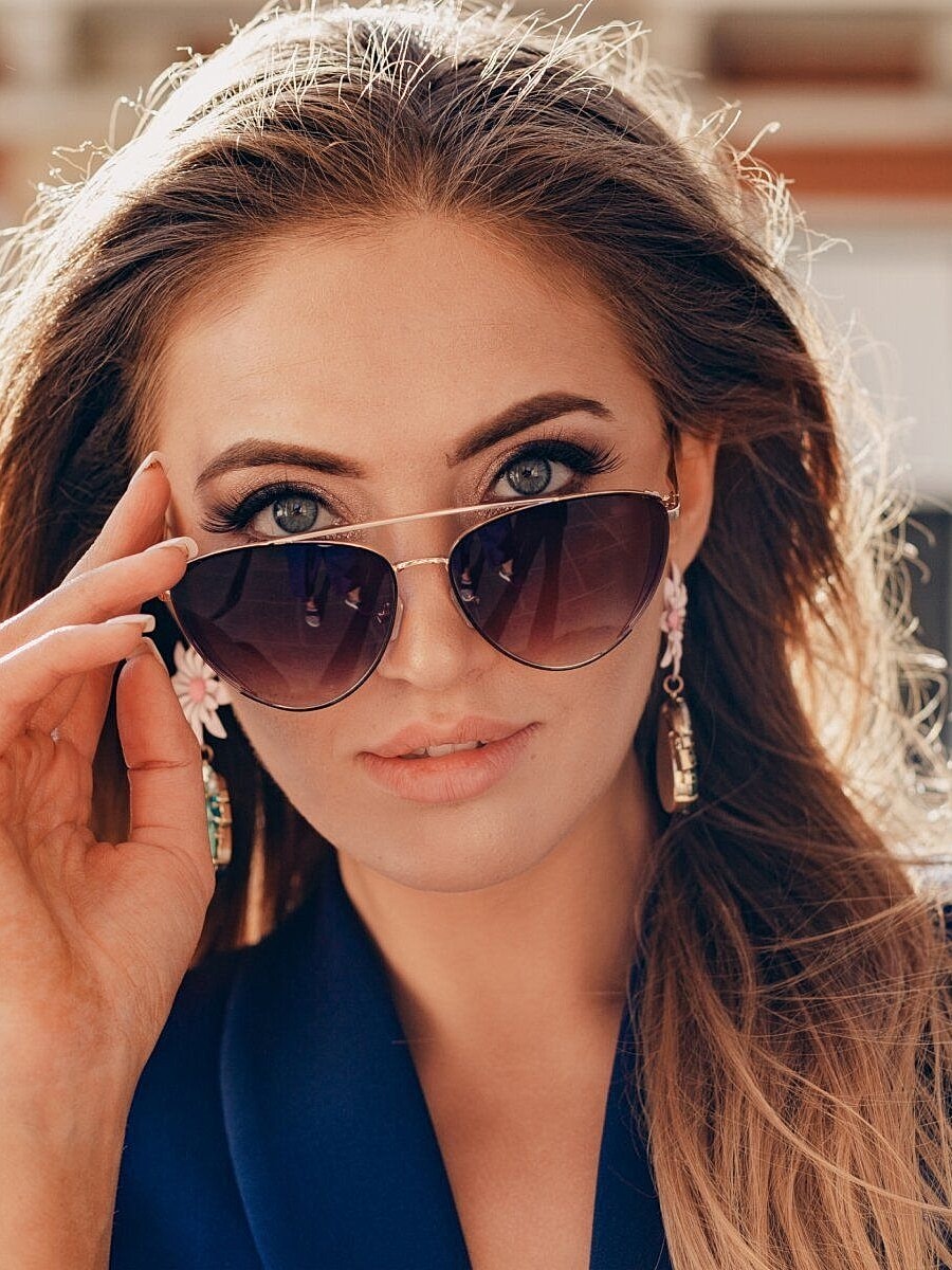 Woman wearing sunglasses and floral earrings.